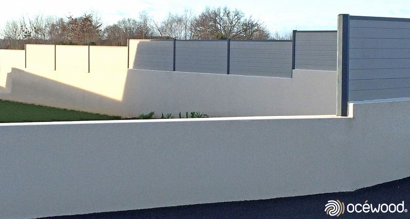 Grande palissade composite gris clair sur muret avec hauteurs différentes