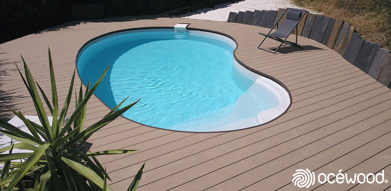 Jolie plage de piscine en lames composites couleur bois, piscine en forme de haricot