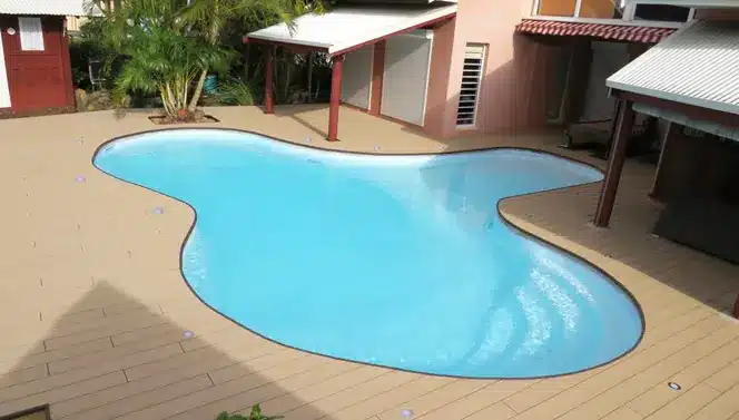 grande piscine aux contours arrondis et plage de piscine en lames composites beige